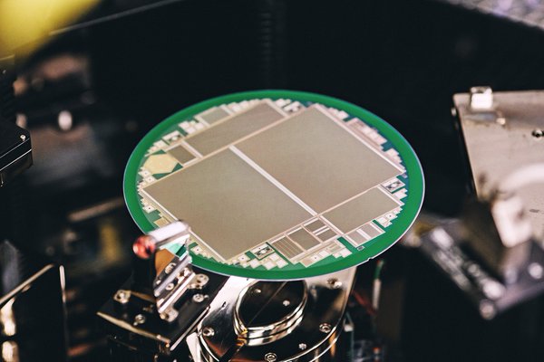 Close-up of a semiconductor wafer with microchip circuits on a machine in a manufacturing environment.